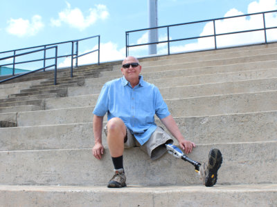 Man with prosthetic leg seated on concrete bleachers